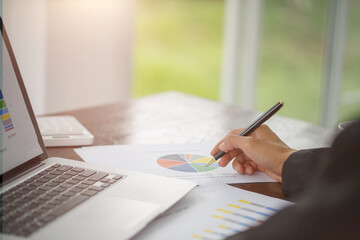 Hand of businessman writing on paper in office, graphs showing the results of their successful teamwork,