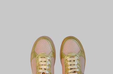 fashionable trendy leather golden children's or women's sneakers, stylish shoes in the autumn season isolated on colored background.