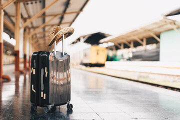 Summer travel concept. Luggage with .straw hat on train station near railway. - obrazy, fototapety, plakaty
