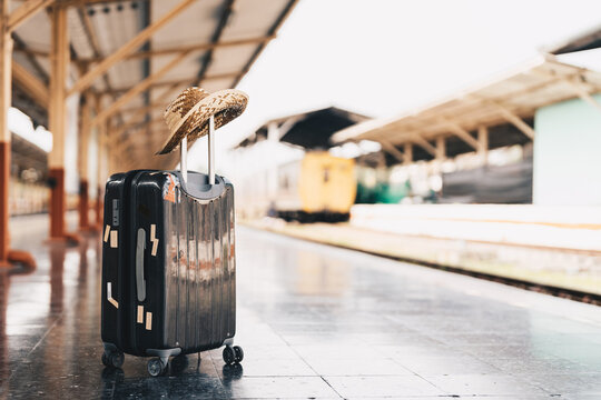 Summer Travel Concept. Luggage With .straw Hat On Train Station Near Railway.