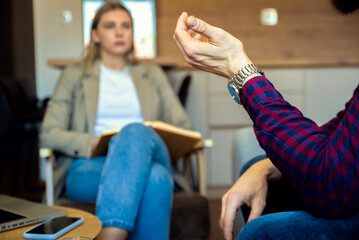 Female psychologist talking to young man during session.