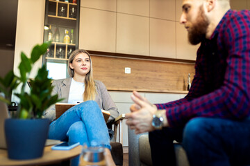 Female psychologist talking to young man during session.