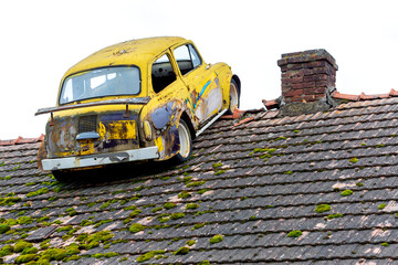 Old, destroyed car on the roof of the house.