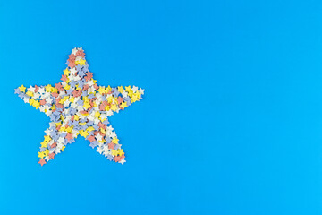 Star made of small colorful stars on blue background.