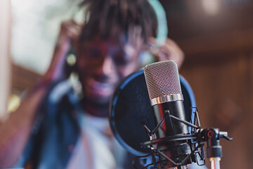 condenser microphone with antipop in front of the blurred face of an African guy singing or talking...