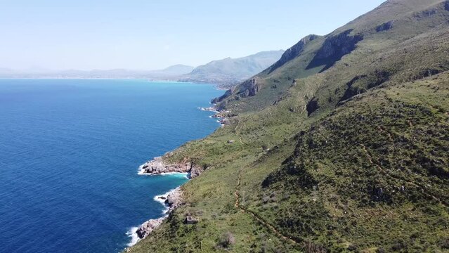 flight from zingaro westwards on the north coast of the island of sicily in italy, lush green hills with deep blue sea, nice weather