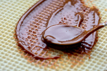 The confectioner with a spoon greases the mixture of condensed milk, cocoa and butter on the waffle cake.