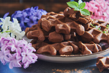 Chocolate Belgian waffles, sprinkled with cocoa, on a ceramic plate.