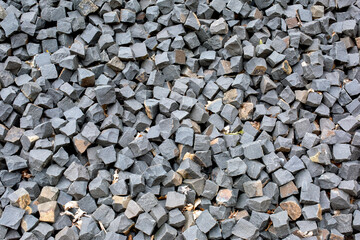 Many square stones for paving the road lie on the road as background, texture, pattern.