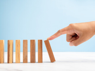Risk and strategy in business concept. Close-up of hand push a wooden block on a line of domino