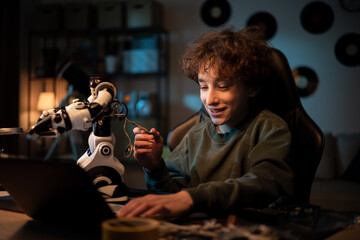 A school-age boy develops a passion for electronics. The child assembles a robot, looks for instructions, help on the internet, scrolls on a laptop, pulls cables from a toy
