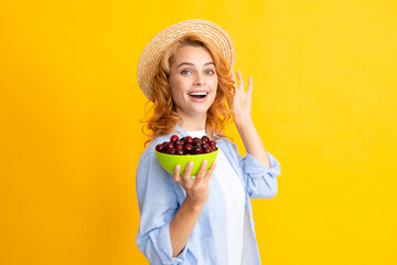 Attractive young woman eating fresh cherry. Healthy summer fruits. Yellow background. Beautiful...