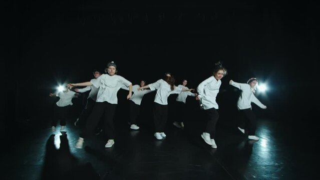 A youth team of dancers in identical clothes spark off the stage. They make clear, practiced movements in sync. They do hip hop