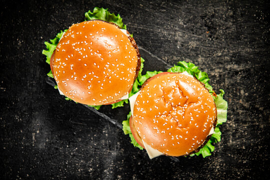 A burger on a stone board on a table. On a black background. High quality photo