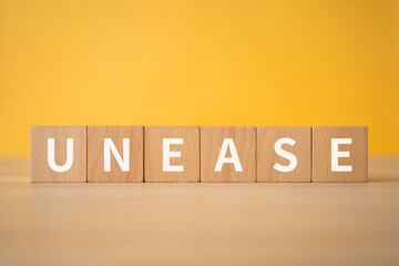不安のイメージ｜「UNEASE」と書かれた積み木