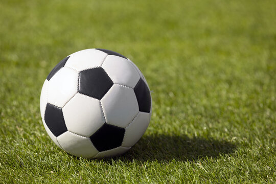 Classic soccer football ball on grass pitch. Side view on retro classic football ball. Image of sports soccer background
