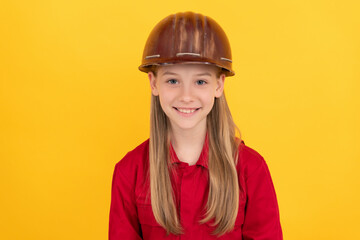 cheerful teen child in builder helmet on yellow background