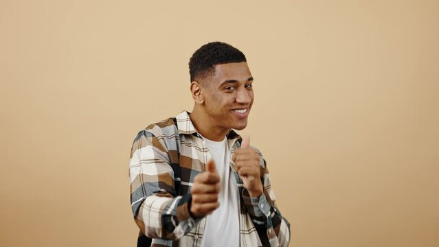 Young playful african american guy flirting to camera, pointing with fingers and showing thumbs up