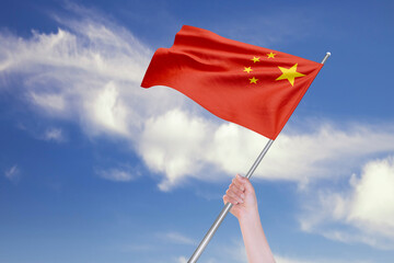 Female Hand is Waving Chinese Flag Against Blue Sky with Clouds