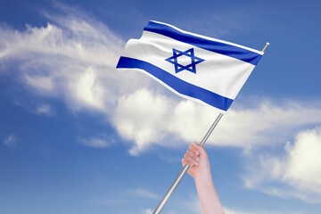 Female Hand is Waving Israeli Flag Against Blue Sky with Clouds