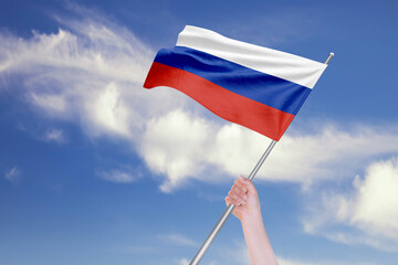 Female Hand is Waving Russian Flag Against Blue Sky with Clouds
