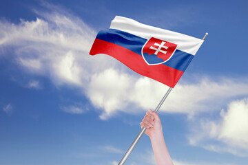 Female Hand is Waving Slovakia Flag Against Blue Sky with Clouds