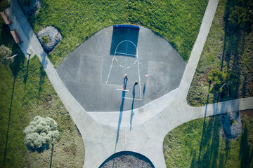 Top down drone shot of people playing basketball on a half court
