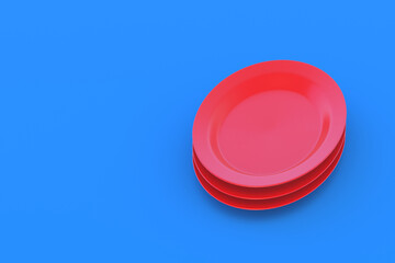 Stack of red plates on blue background. Copy space. 3d render