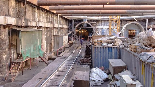 Cargo train in large huge ditch pit tunnel timelapse. Reinforcing structures from thick iron pipes of beams and structures at the construction site of the underground metro station line.