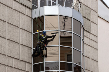 A worker washes window on the facade of a building