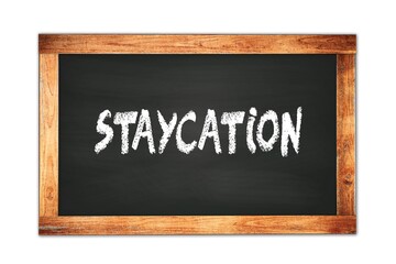 Obraz premium STAYCATION text written on wooden frame school blackboard.