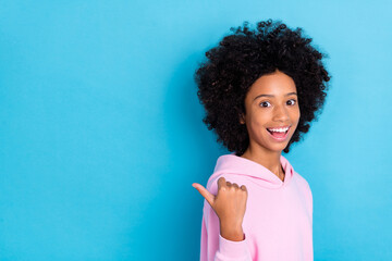 Profile side photo of youth excited girl indicate finger empty space direct suggest proposition isolated over blue color background