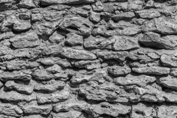 Black and white photo of a fragment of a wall made from rough stone