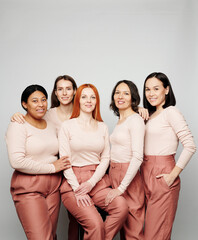 Portrait of smiling multi-ethnic women in pink outfits standing against white background, every woman is unique concept