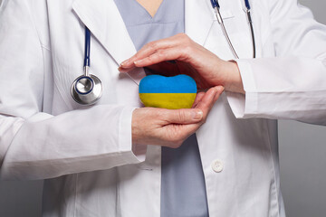 Doctor hands holding and caring heart with color of the Ukraine flag. Concept safety, health care and medicine in Ukraine - obrazy, fototapety, plakaty