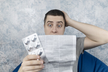 Man on a white background reads the instructions for medicines. Male looks at the list and...