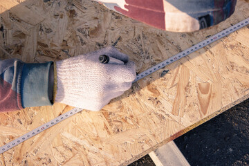 Hands of a worker in gloves close-up. A builder with gloved hands draws and measures the size of...