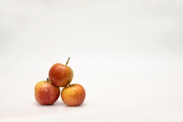 Red ripe apples of a new crop are stacked in a small pyramid on a white background for a photo studio. 