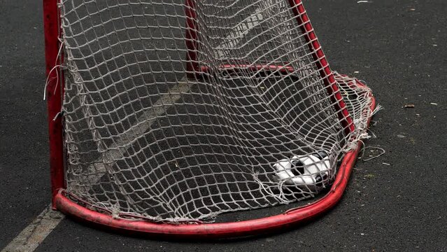 Woman kick deflated soccer ball into mini football goal from close distance, slow motion shot. Ball hit the net and fall down on ground
