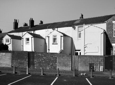view of the back of a row of white and yellow painted typical small english terraced houses with parking spaces in fleetwood lancashire