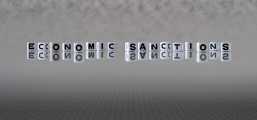 economic sanctions word or concept represented by black and white letter cubes on a grey horizon...