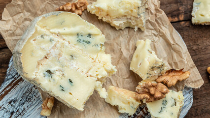 Danish blue cheese. Tasty blue cheese on a wooden background and burlap. Dorblu cheese pieces