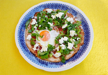 Homemade pizza with egg, spring onion, bacon, cheese and rucola. Top view of pizza	