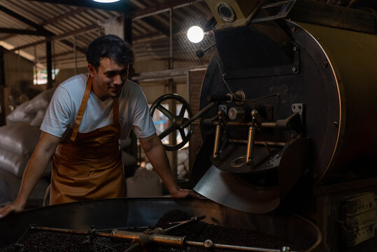 Private business owner controlling coffee roasting process. Coffee roaster working on roasting equipment.
