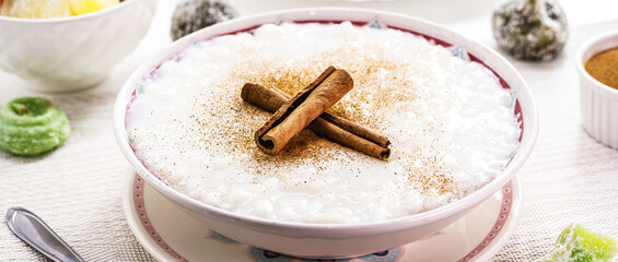 large bowl with sweet rice pudding, with cinnamon stick and cinnamon powder, homemade dessert, typical sweet from Brazil in the June festivals
