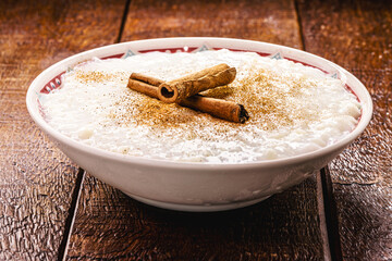 sweet rice pudding, with cinnamon stick and cinnamon powder, homemade dessert, close up and copyspace