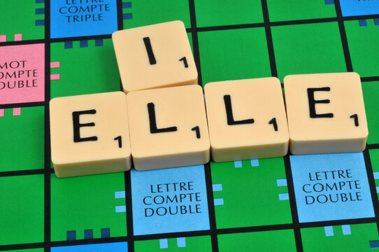 Lettres formant les pronoms il et elle sur un jeu de scrabble