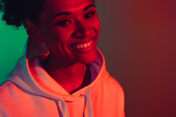 Cropped view portrait of attractive cheerful friendly girl isolated over bright multicolor gradient...