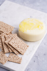 Healthy crunchy crisp crackers with sesame seeds and round cheese kashkaval on marble board