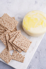 Healthy crunchy crisp crackers with sesame seeds and round cheese kashkaval on marble board